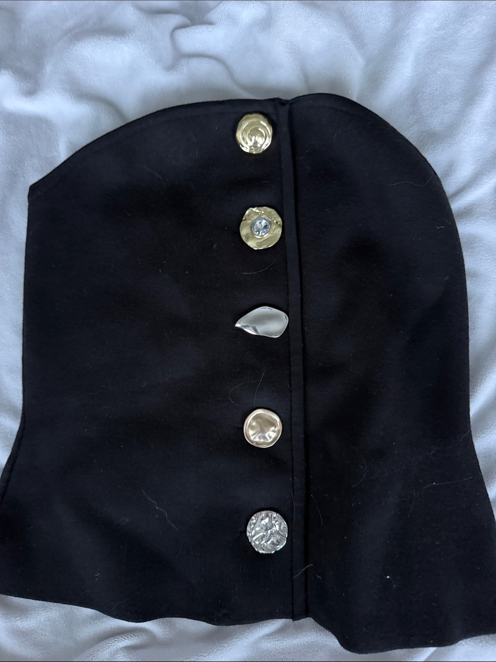 Women's black sleeveless garment with decorative buttons